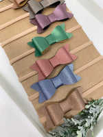 Set of 10 faux leather baby bows.